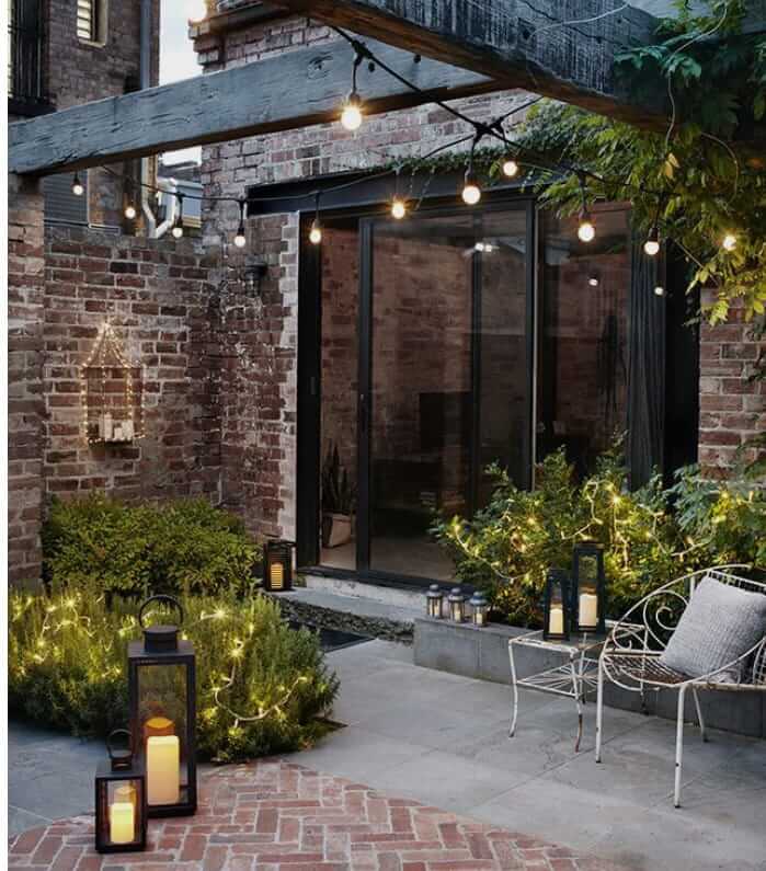 A cozy outdoor space featuring lanterns, string lights, and greenery, showcasing outdoor lifestyle products for relaxation.